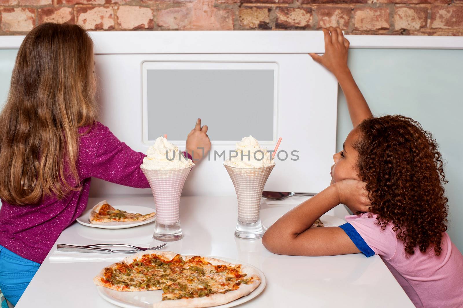 Little girls enjoying pizza in a restaurant by stockyimages