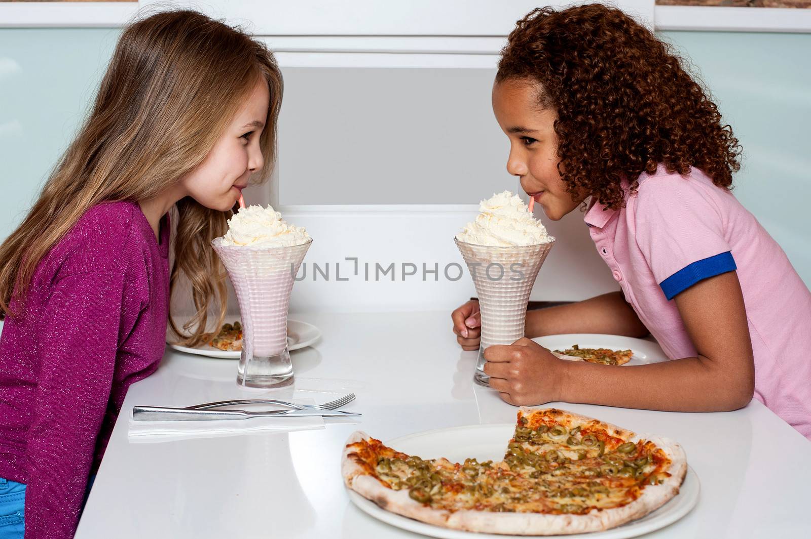 Little girls drinking strawberry shake in a restaurant