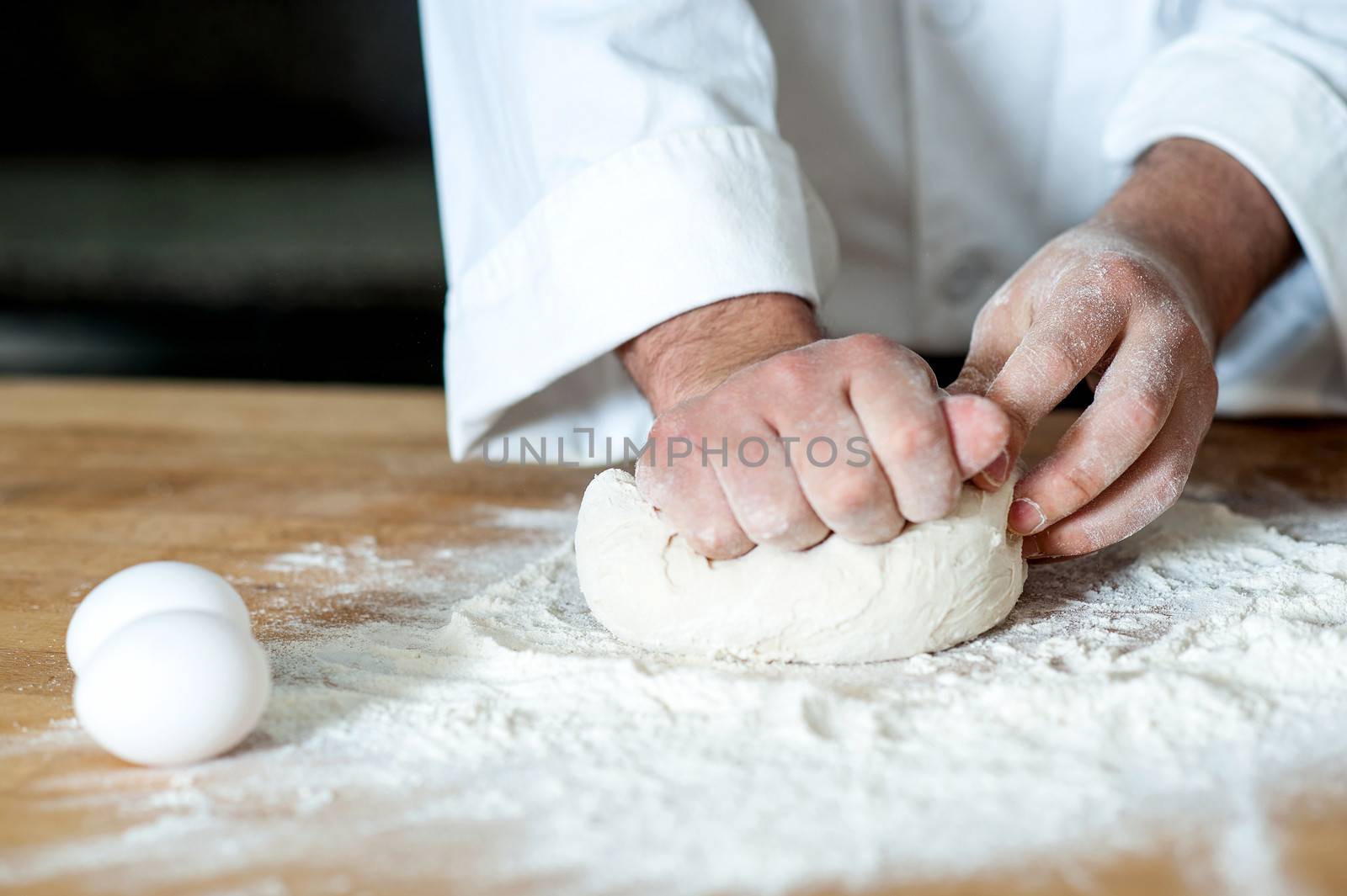Chef kneading dough with eggs beside