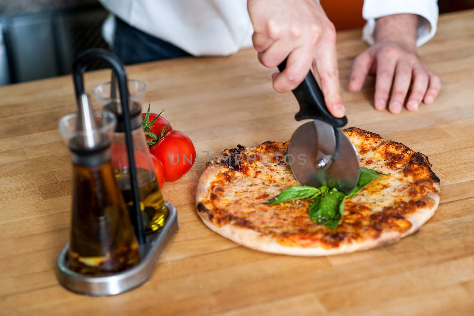 Male chef cutting hot pizza before delivery