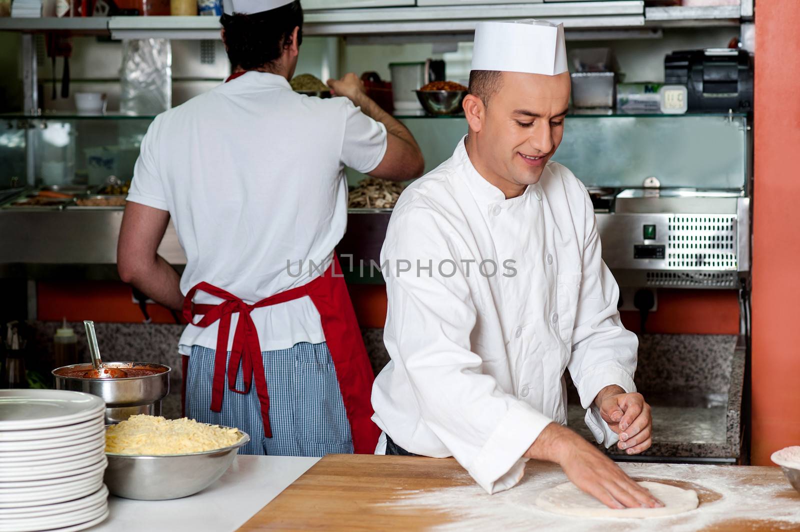 Chef preparing pizza base by stockyimages