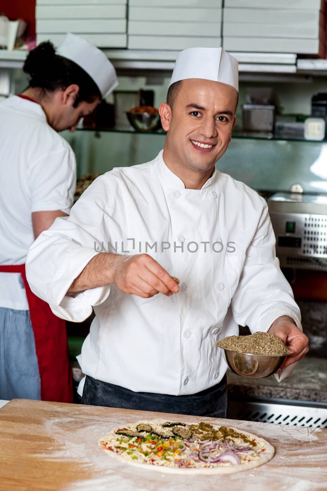 Experienced chef preparing pizza in kitchen
