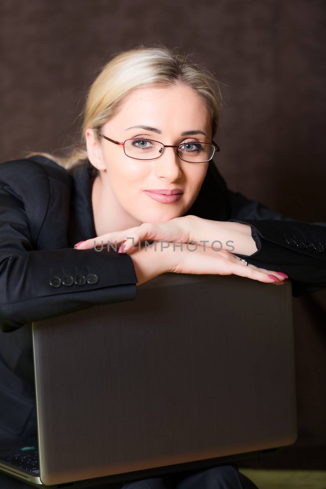 Portrait of business woman with laptop on dark background