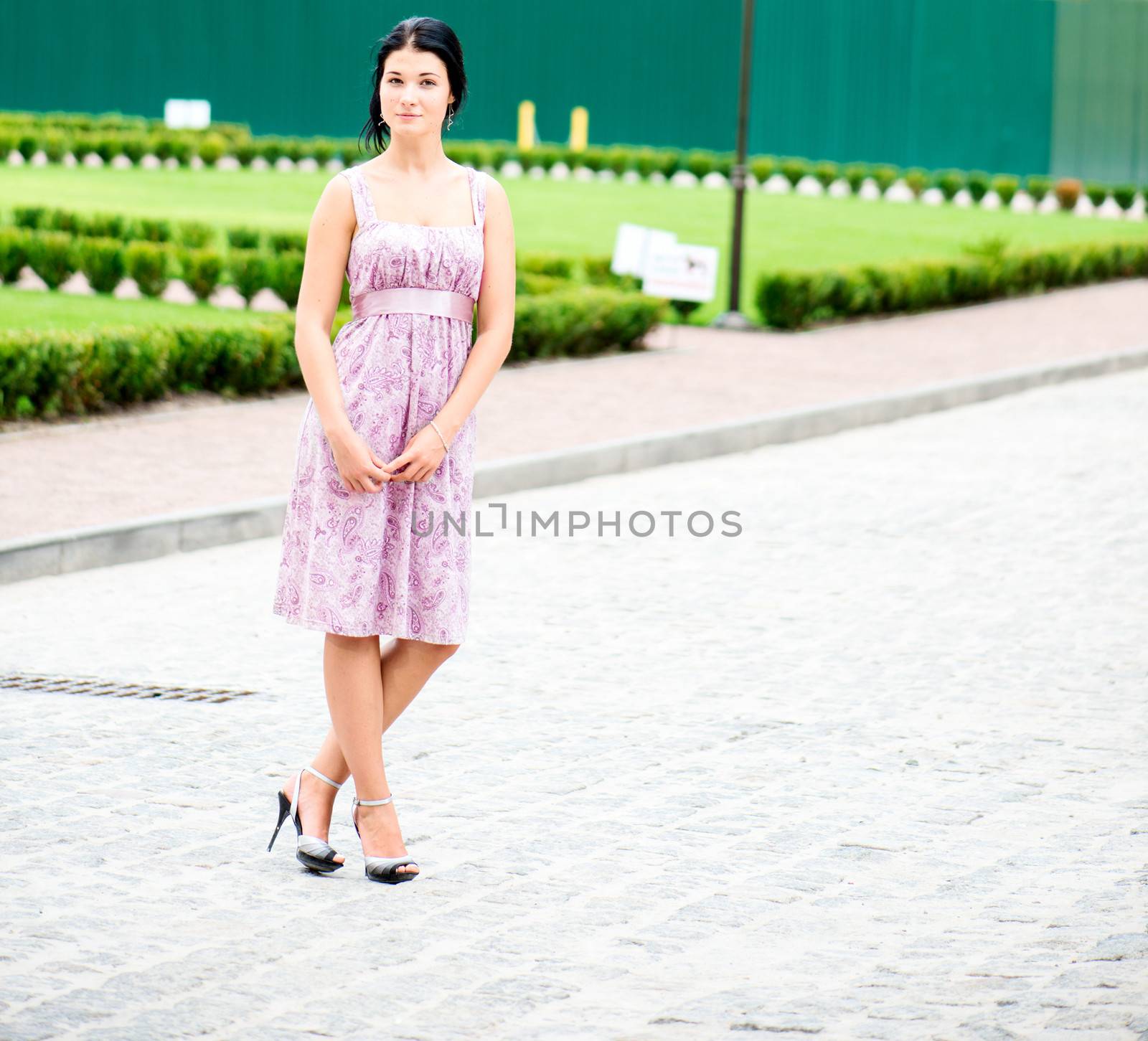 Young beautifull woman standing in a dress on street
