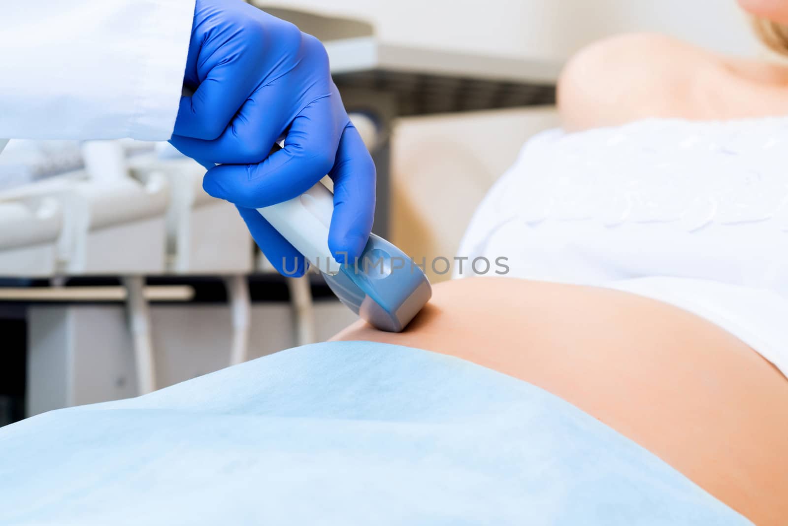 close-up of hands and abdominal ultrasound scanner for pregnant women