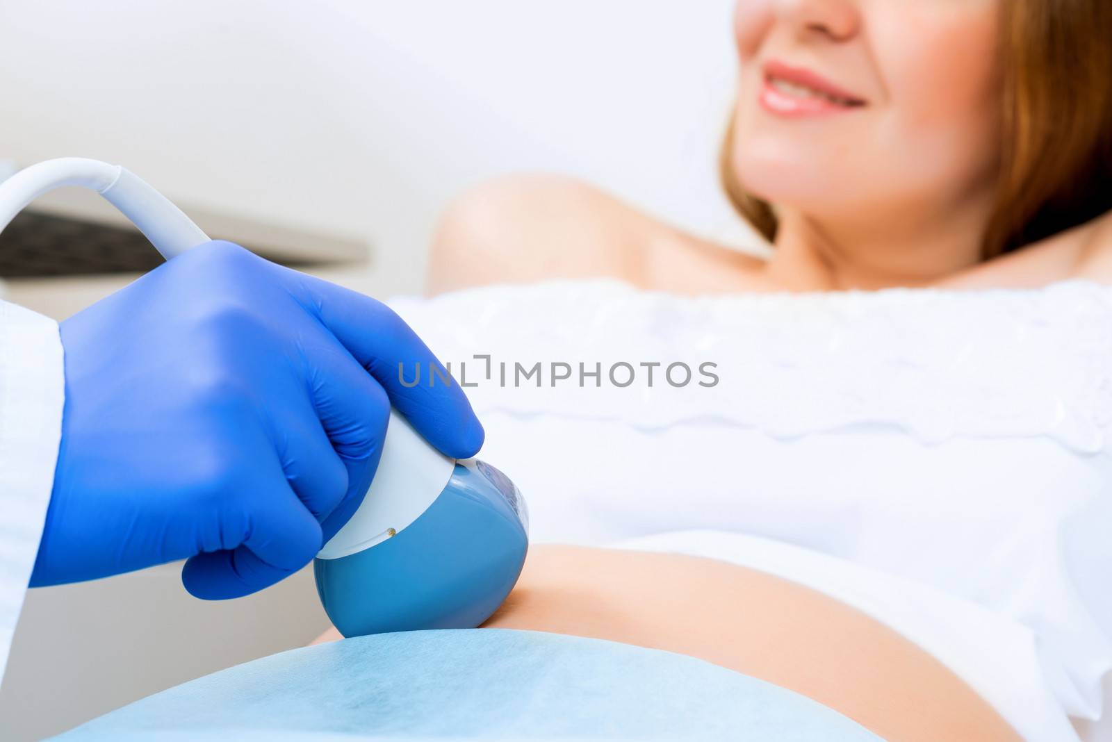 close-up of hands and abdominal ultrasound scanner for pregnant women