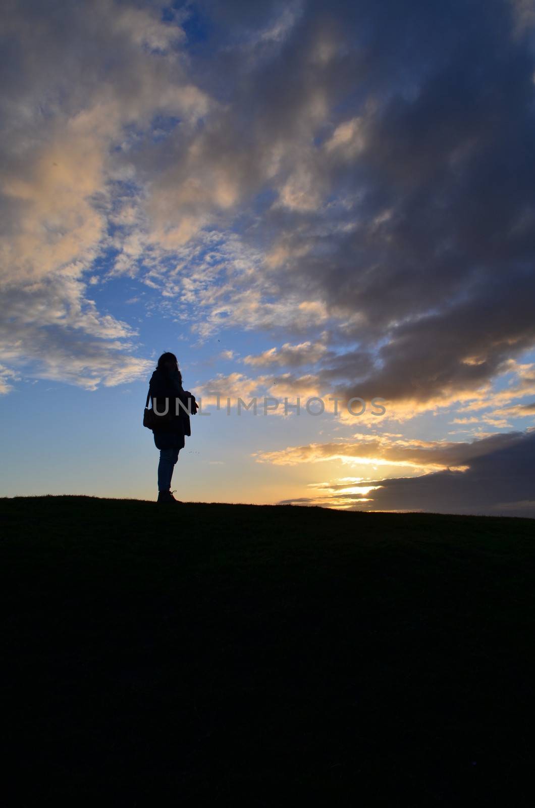 A Woman rambler stands and watches the setting sun.