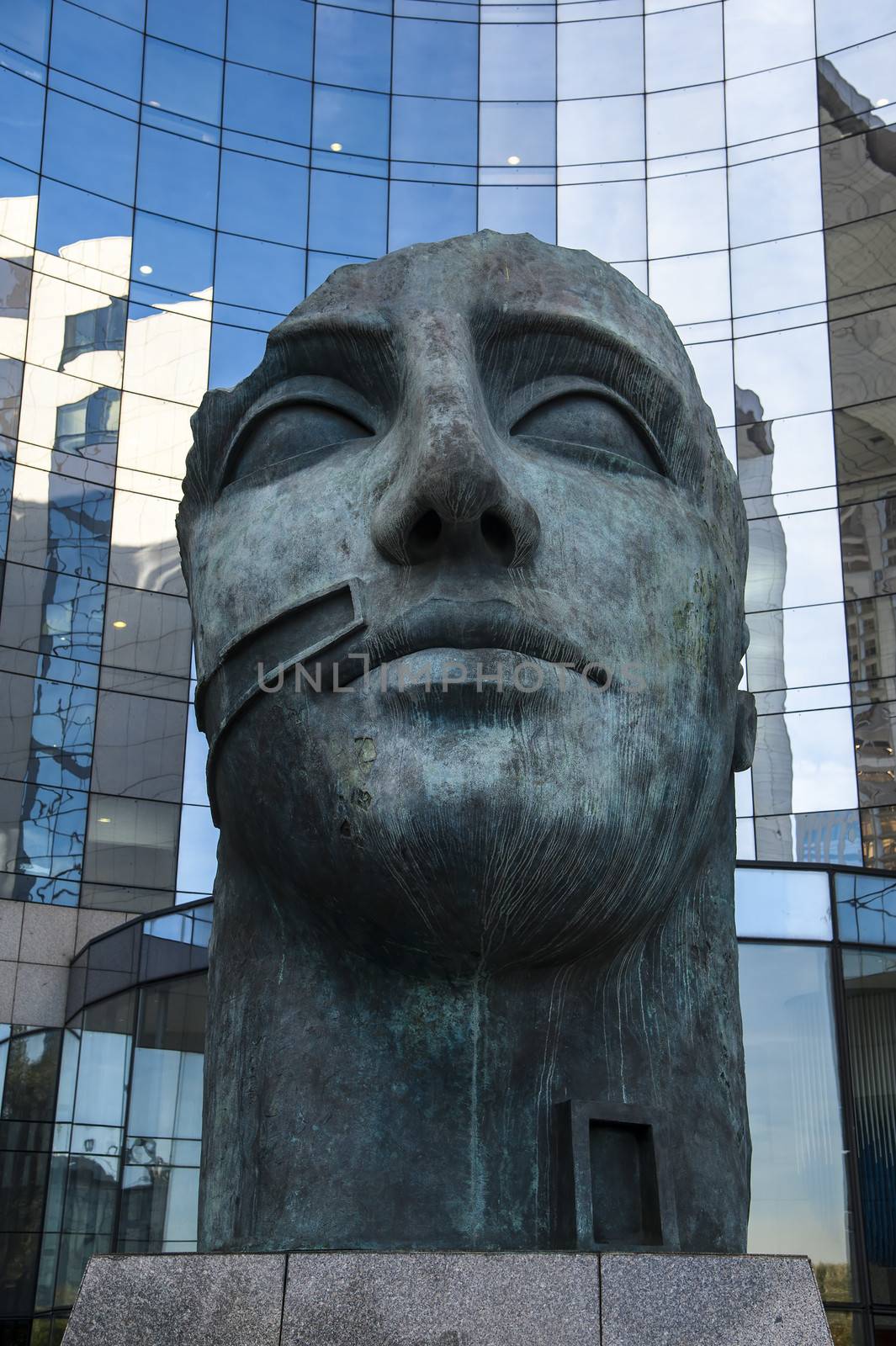 Head statue in front of modern skyscrapers in Paris