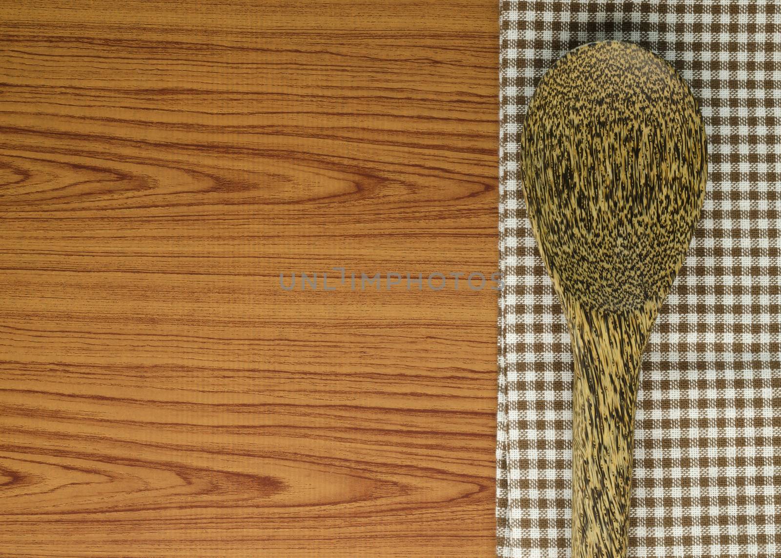 brown kitchen towel with spoon on wood background
