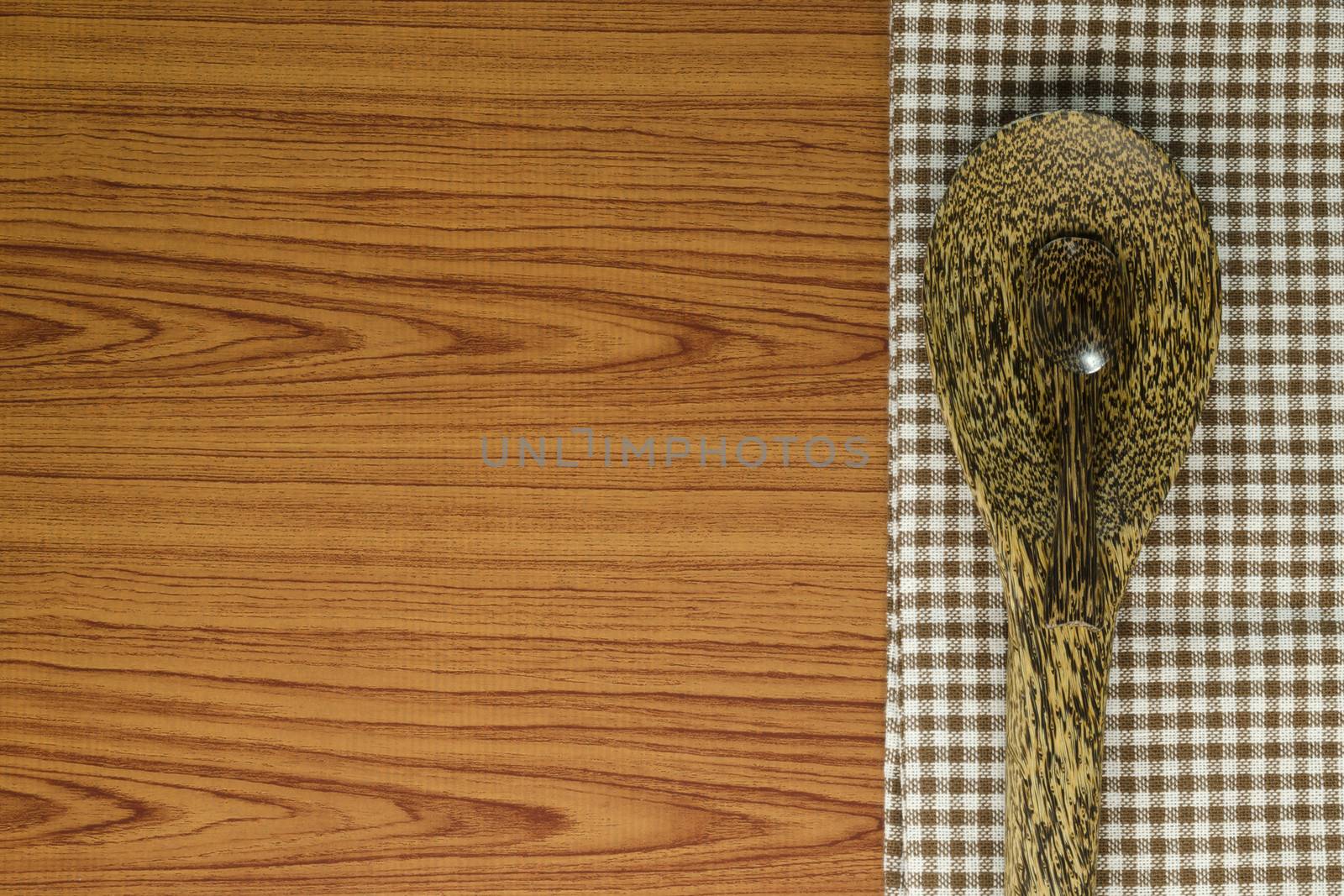 brown kitchen towel with spoon on wood background