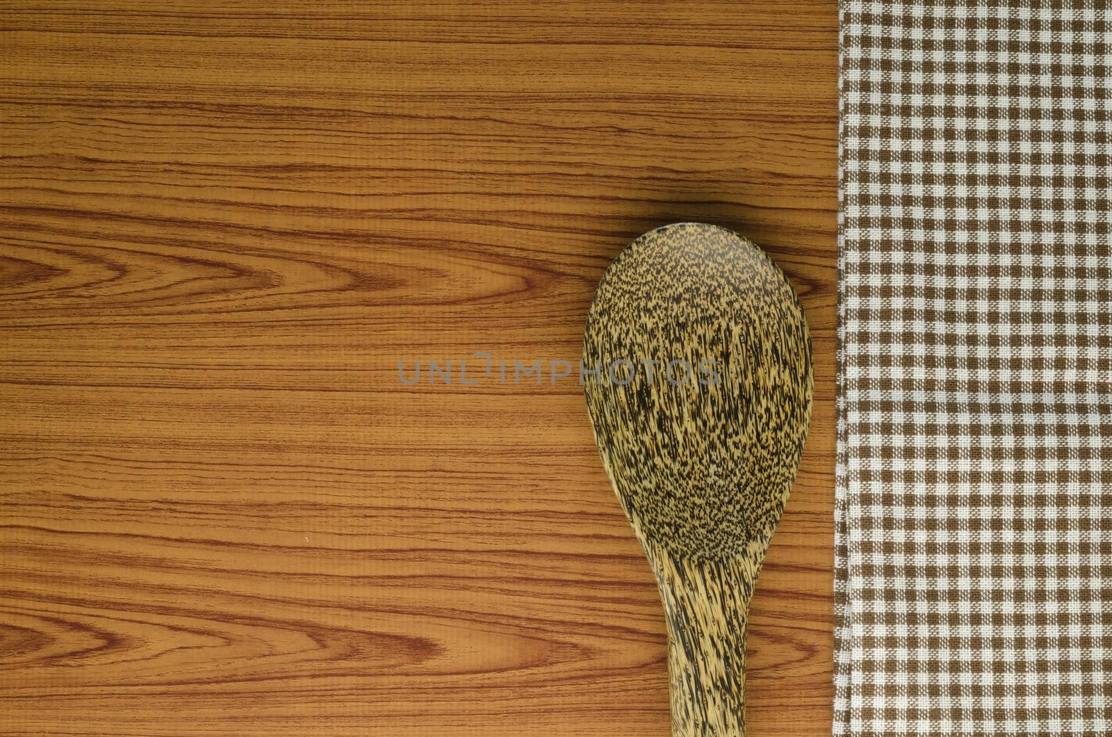 brown kitchen towel with spoon on wood background