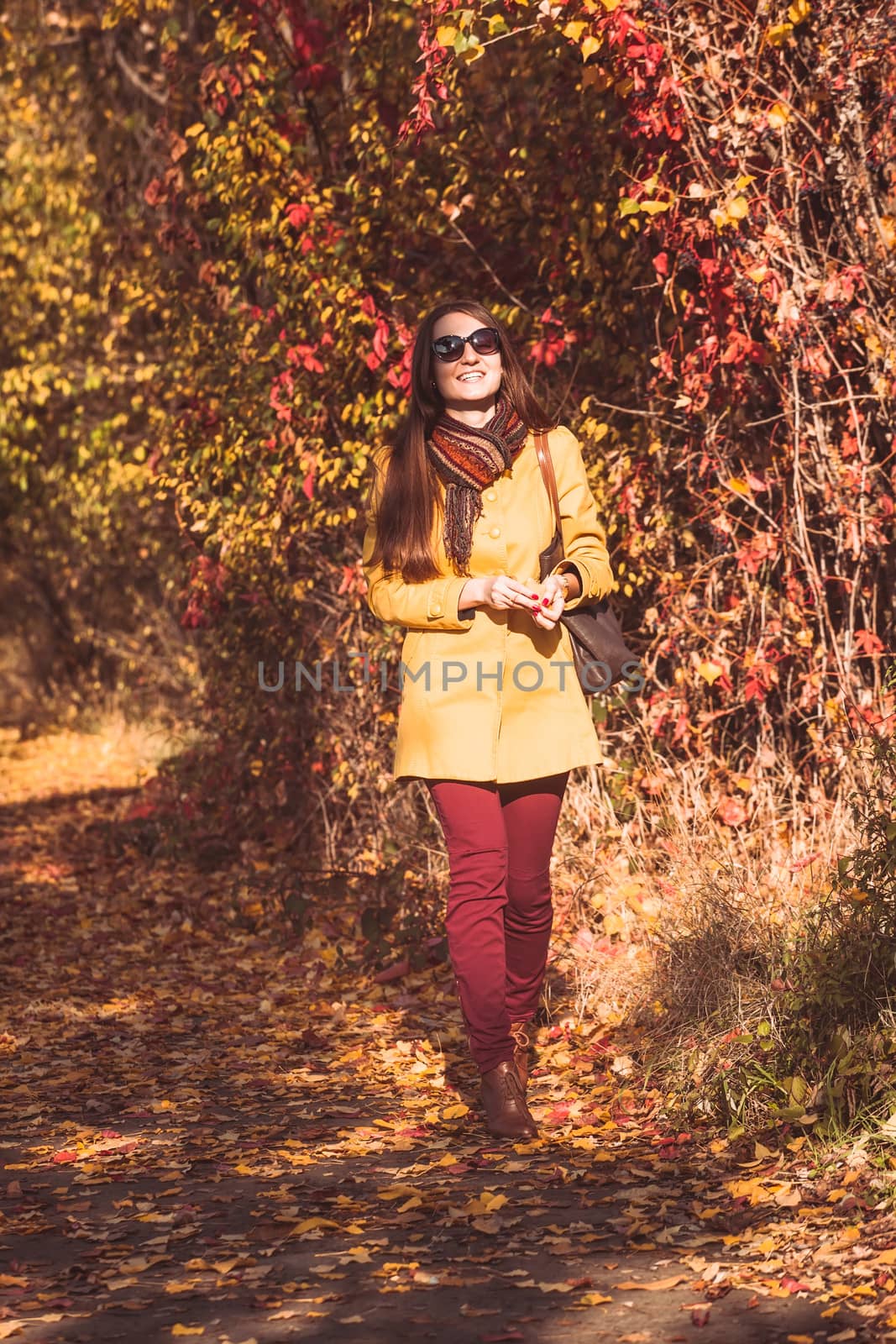 Woman is walking in autumnal park in glasses