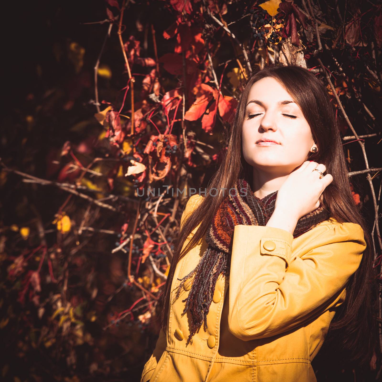 Woman is walking in autumnal park and enjoys the sunlight