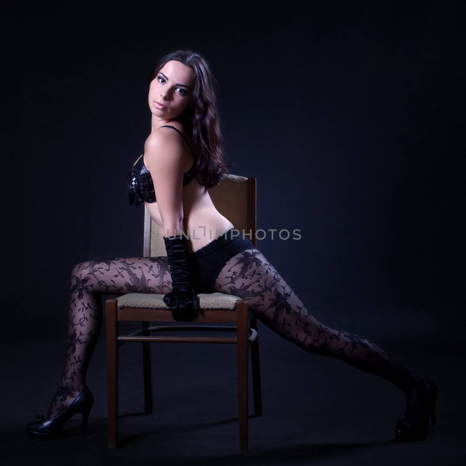 Young woman in bra and patterned stockings makes spread eagle on the chair