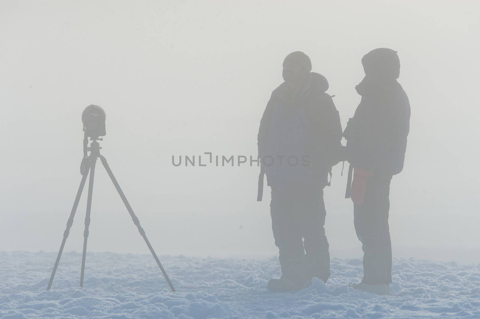 Silhouette of photographers with tripod  in the fog. 