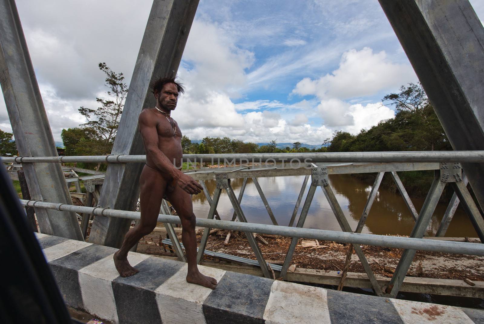 WAMENA, PAPUA, INDONESIA - JUNE, 20:The naked Papuan man goes on the asphalted road on June, 20, 2012 near Wamena, Papua, Indonesia.