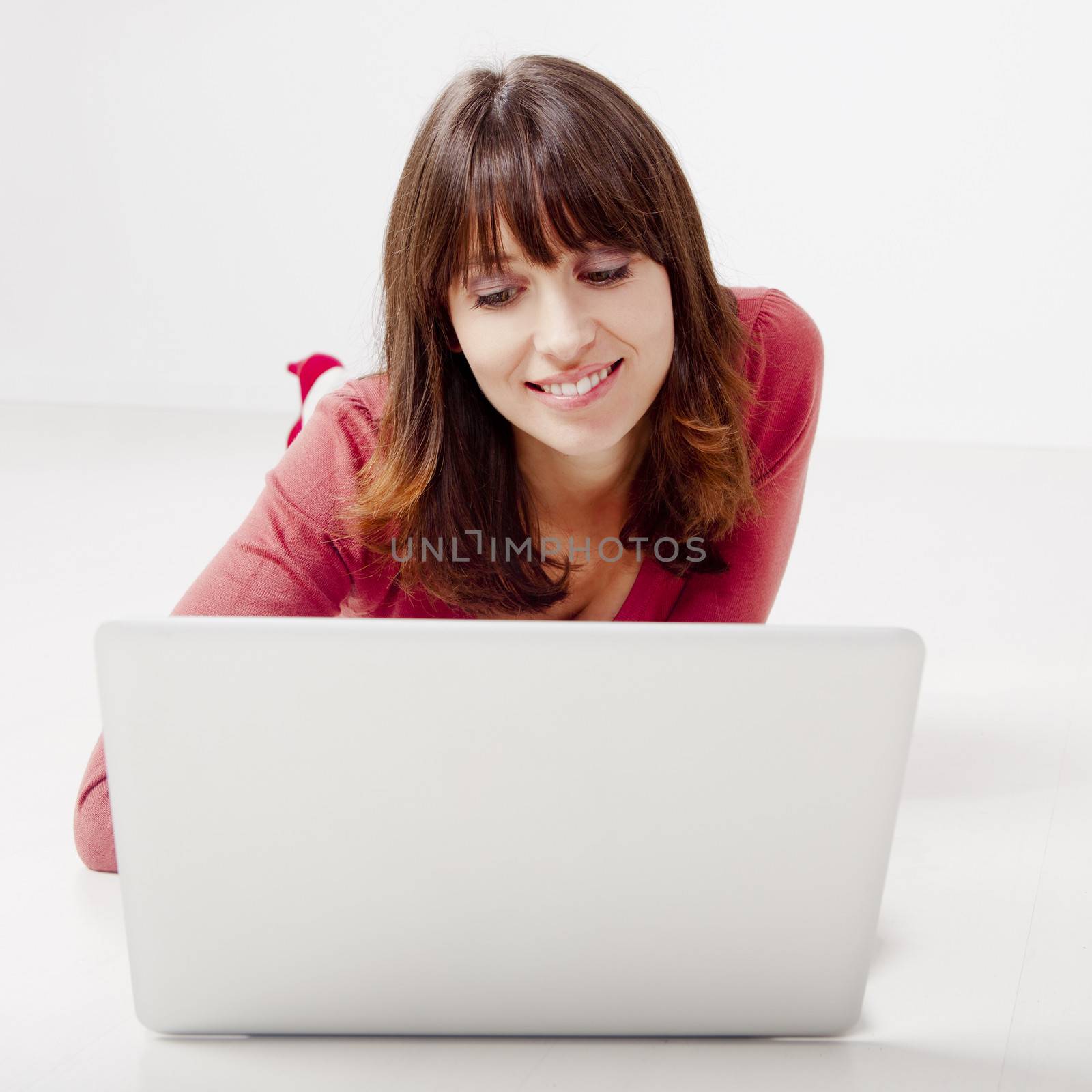 Beautiful woman lying on the floor  working on a laptop