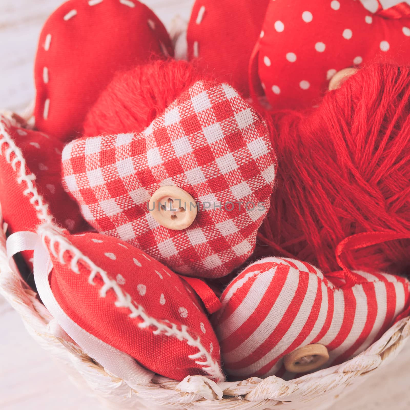 Valentine decorations: textile red hearts in white basket on the shabby table