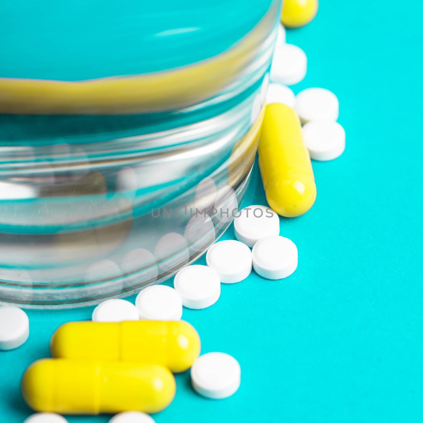 Scattered medicine pills closeup and glass with water. Medicine concept