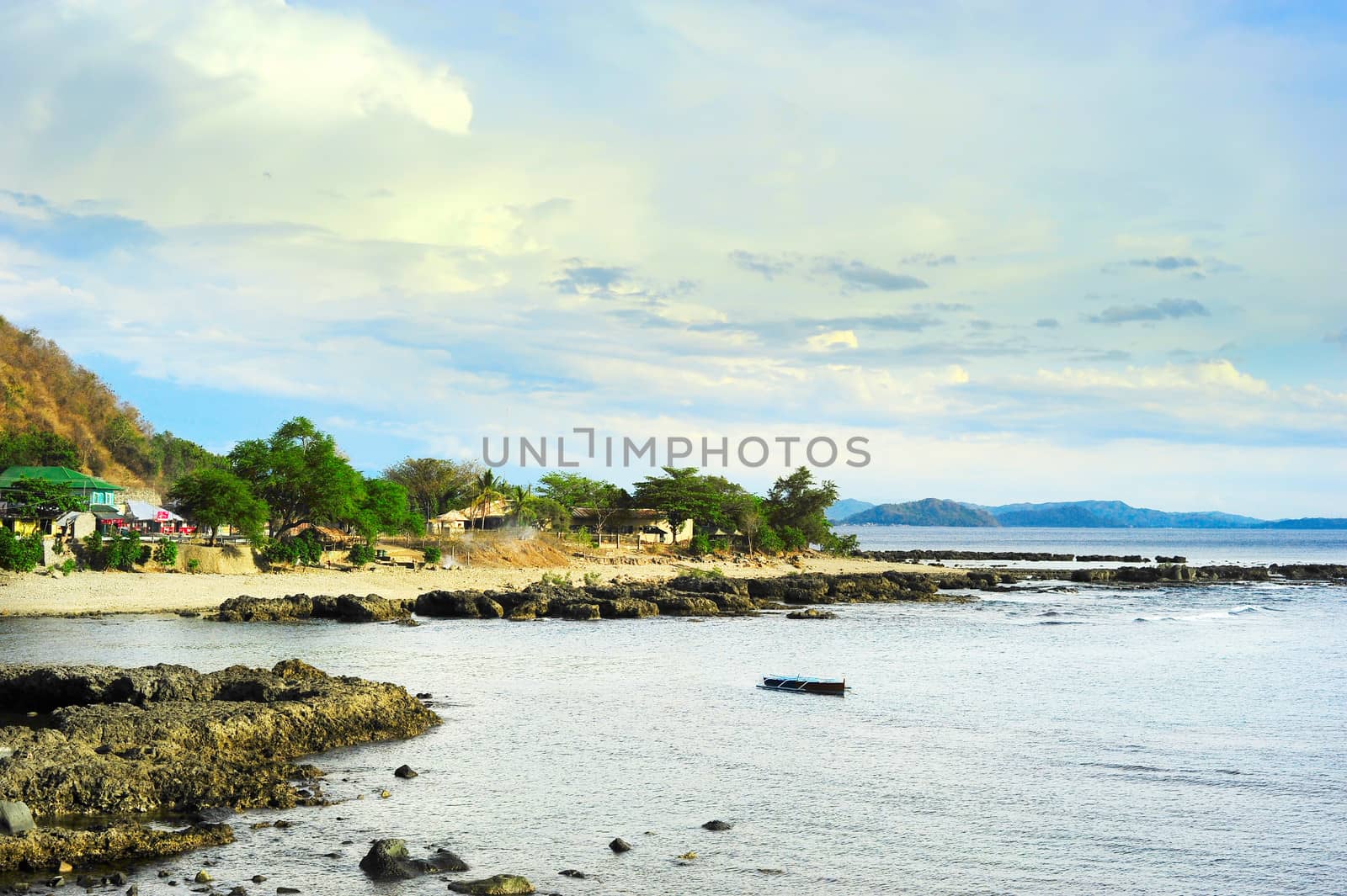 Philippines rocky seashore and village at sunset.