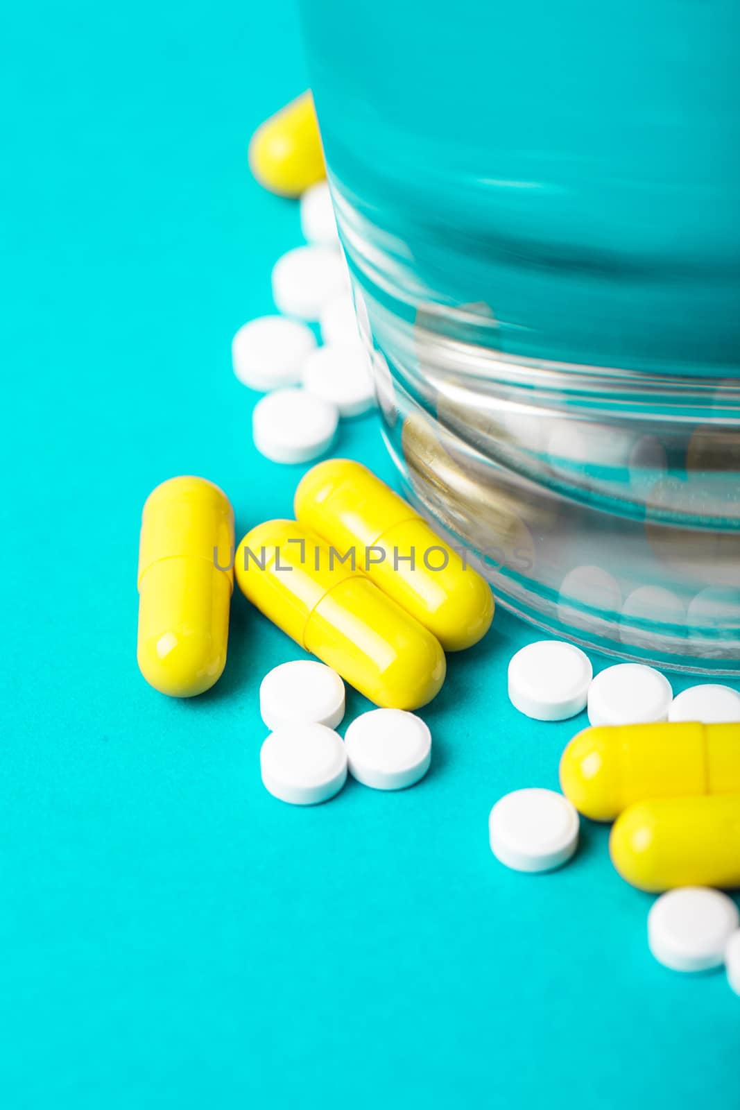 Scattered medicine pills closeup and glass with water. Medicine concept