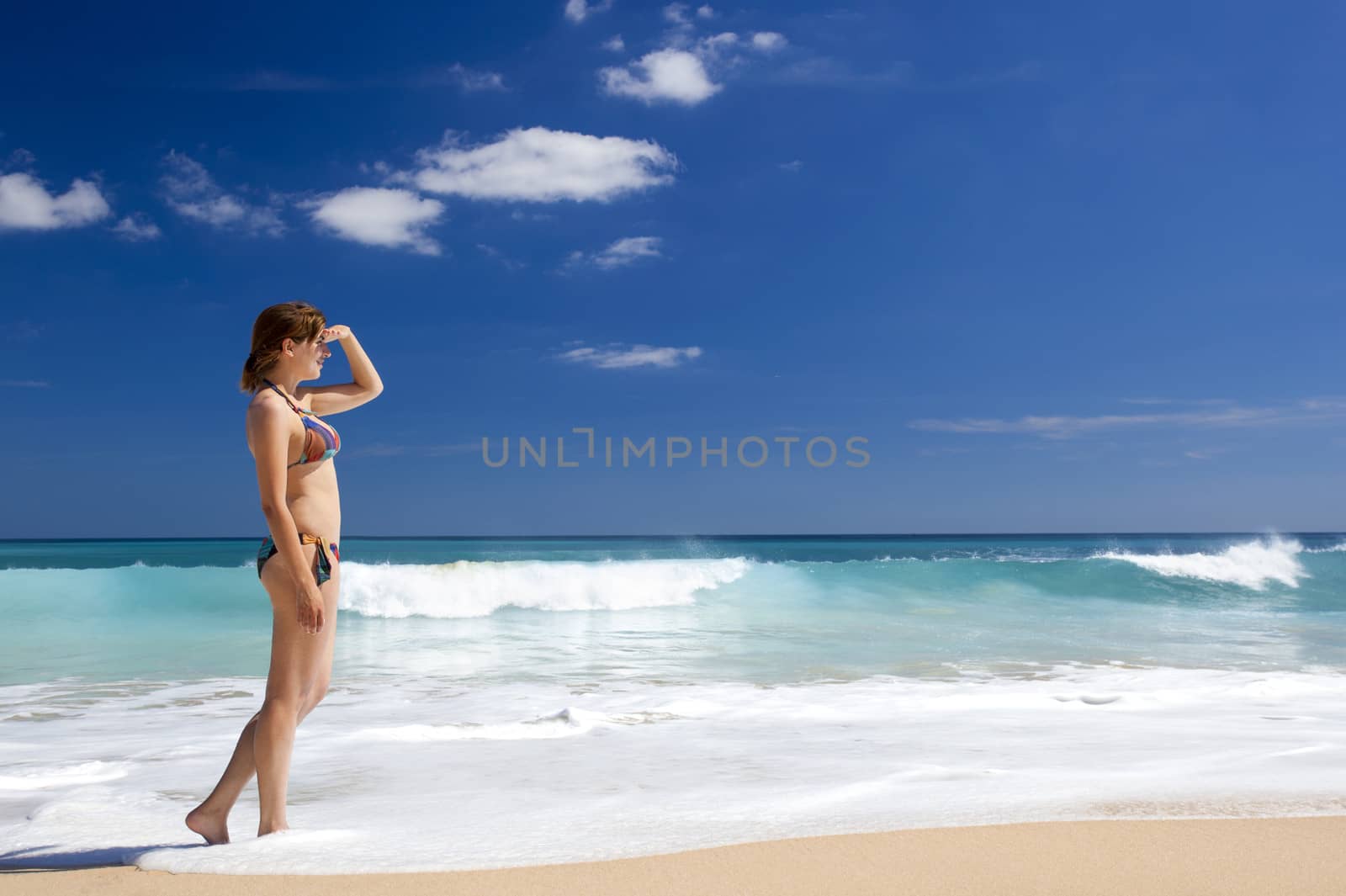 Beautiful young woman in a tropical beach looking somewhere