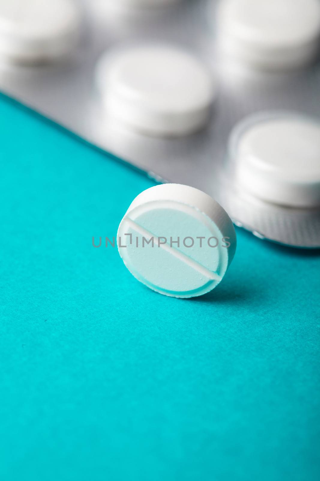 One tablet closeup on background with pack of pill