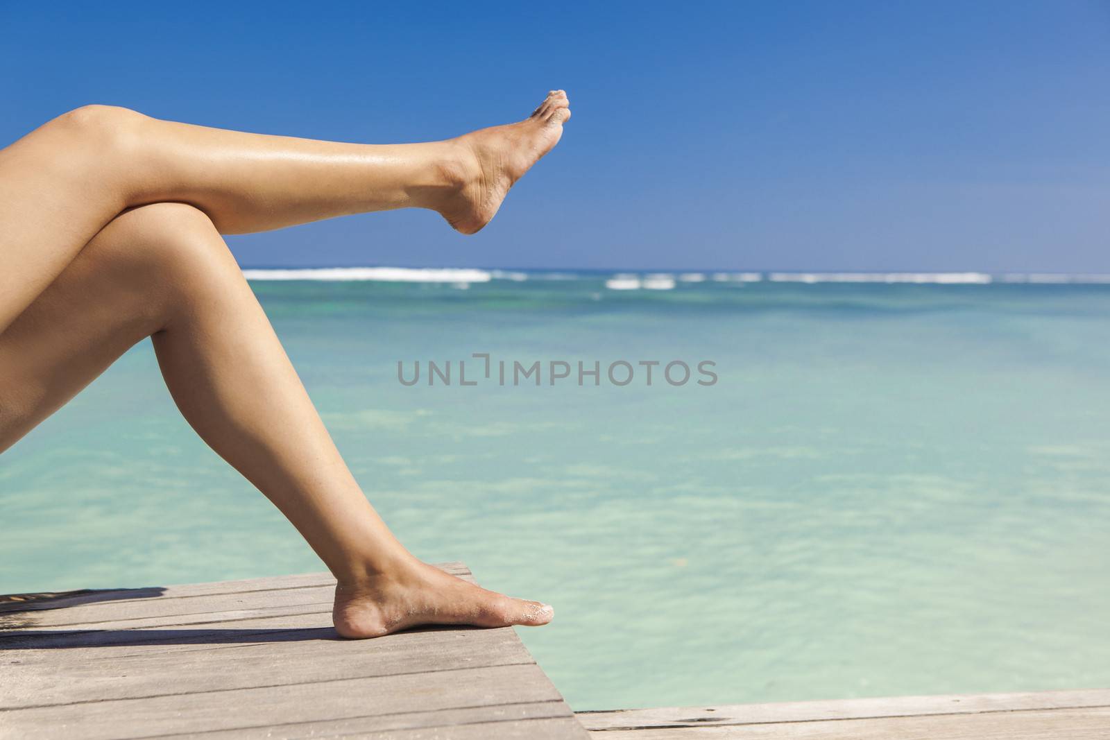 Beautiful female legs with a beautiful tropical beach as background