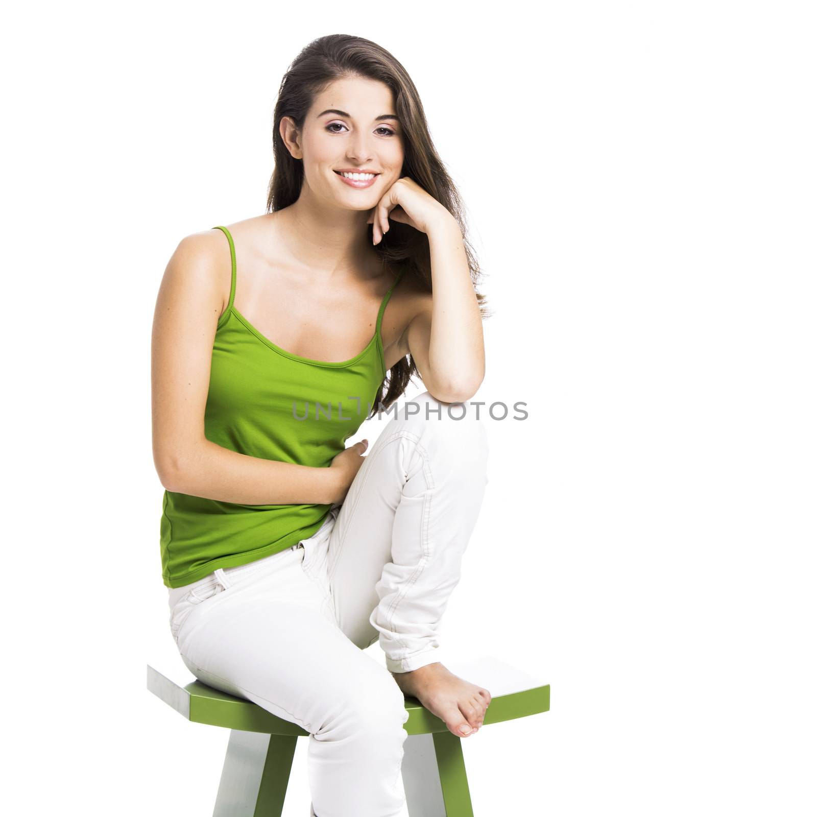 Beautiful young woman sitting in a green chair, isolated over a white background