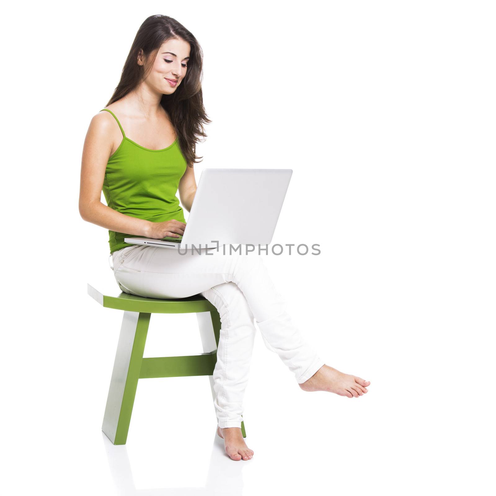 Beautiful woman sitting in a chair working with a laptop, isolated over a white