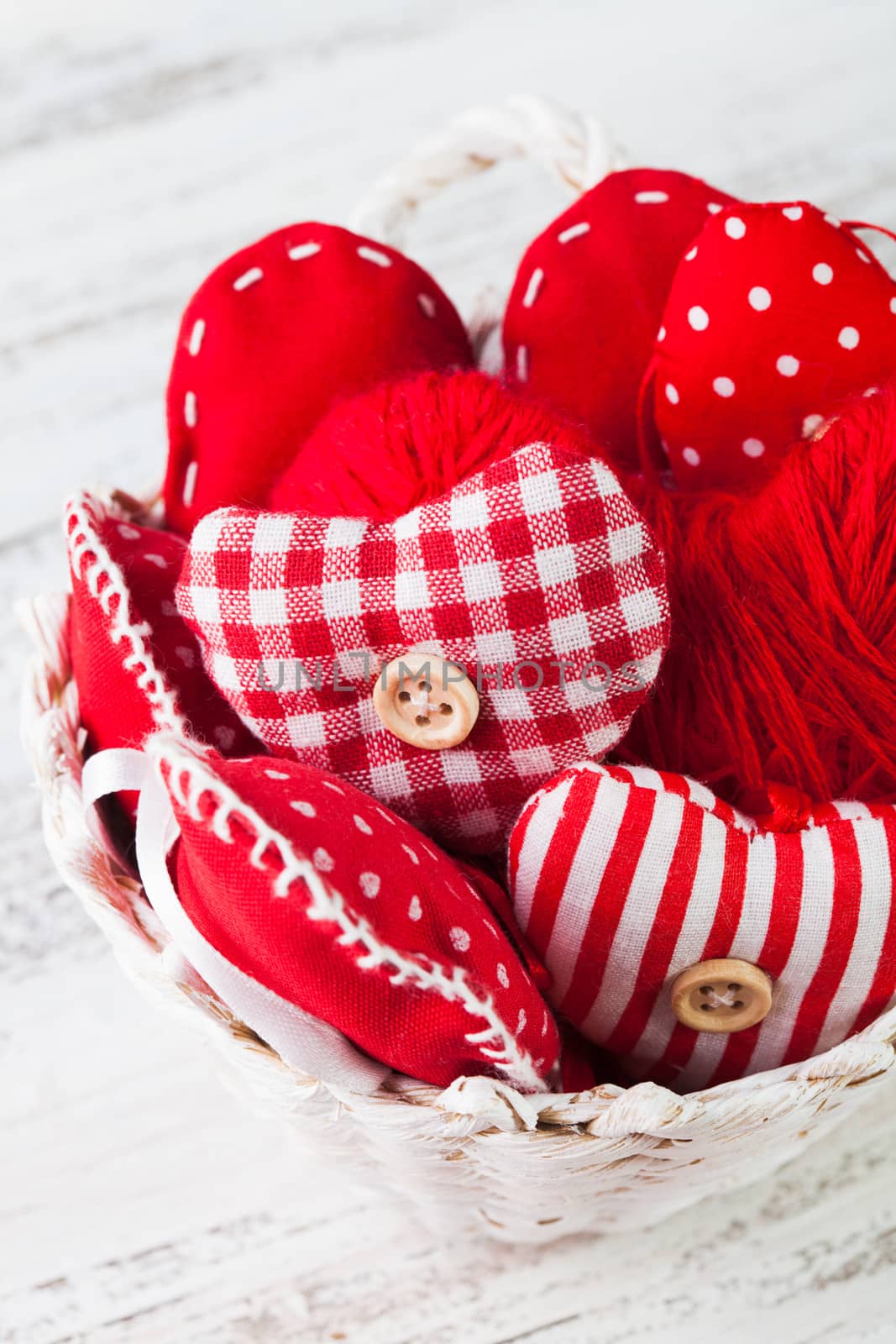 Valentine decorations: textile red hearts in white basket on the shabby table