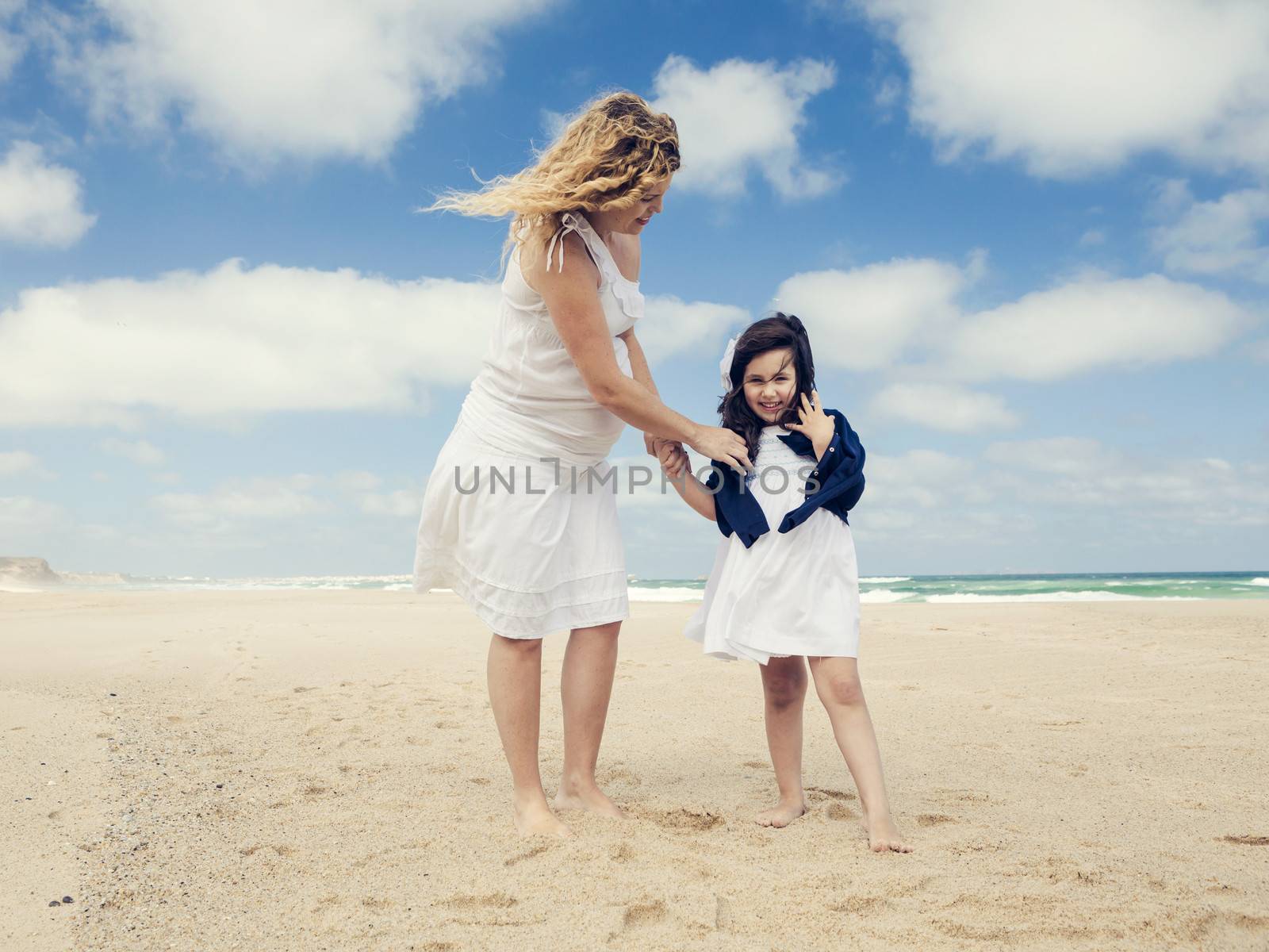 Beautiful pregnant woman and her little daughter on the beach