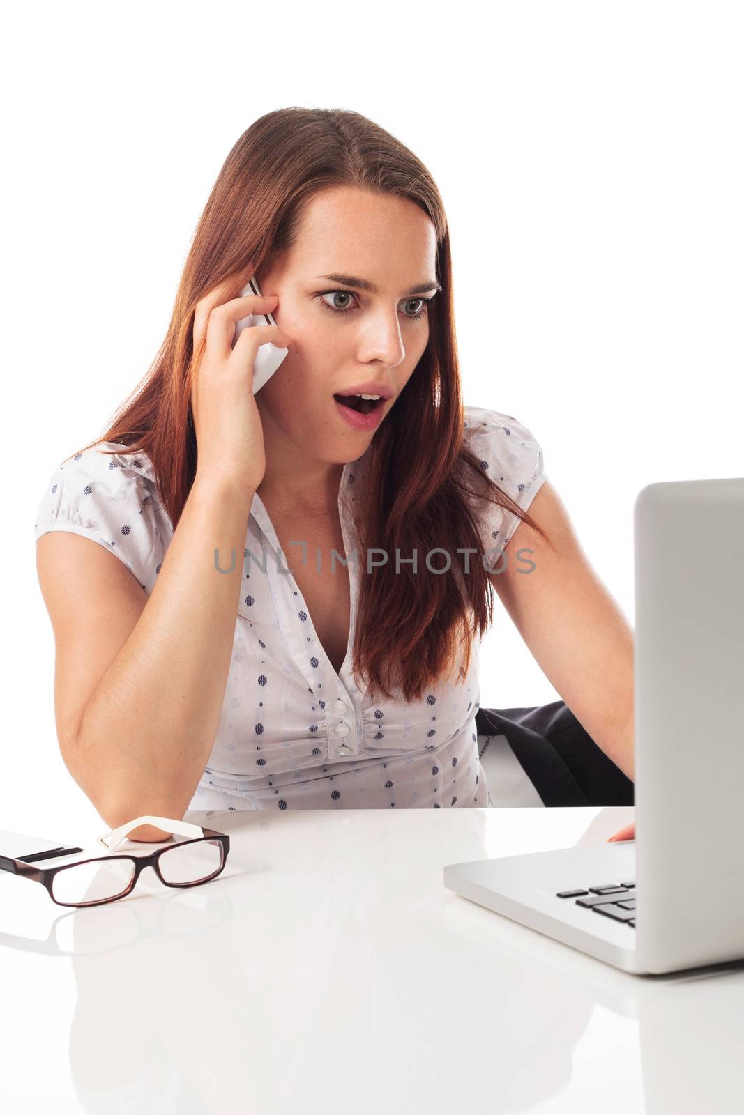 Young cute woman on the phone, working in front a laptop and surprised, isolated on white 