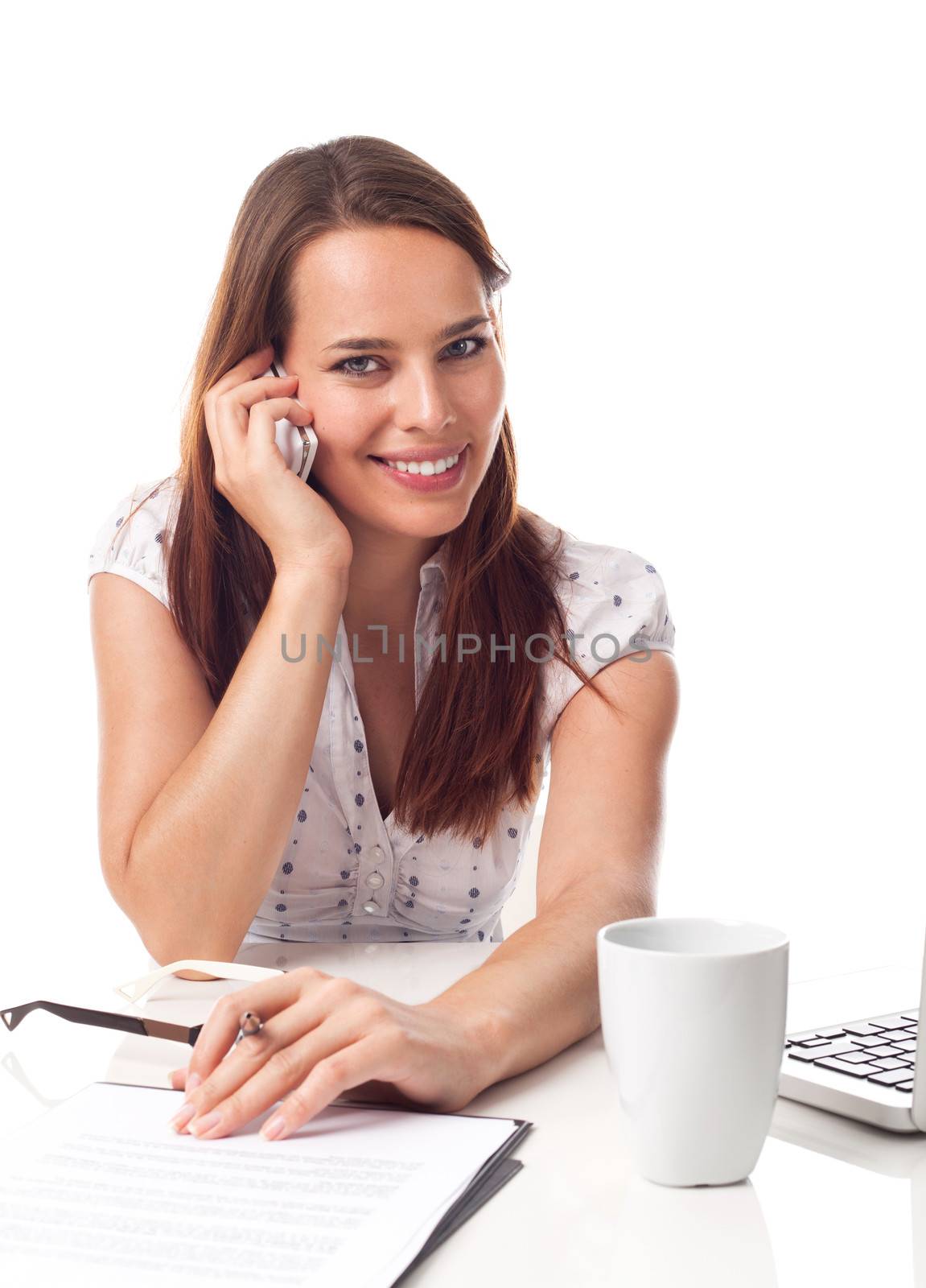 Beautiful young woman phoning, working in front a laptop, isolated on white 