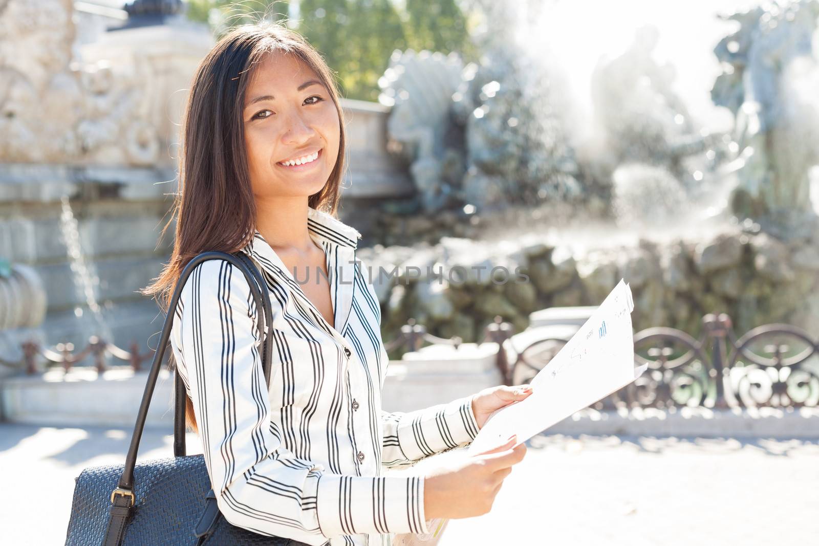 Smiling asian tourist holding a city map