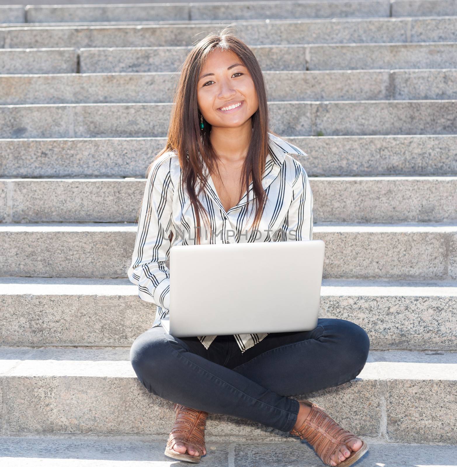 Beautiful asian girl sitting on stairs and using a laptop 