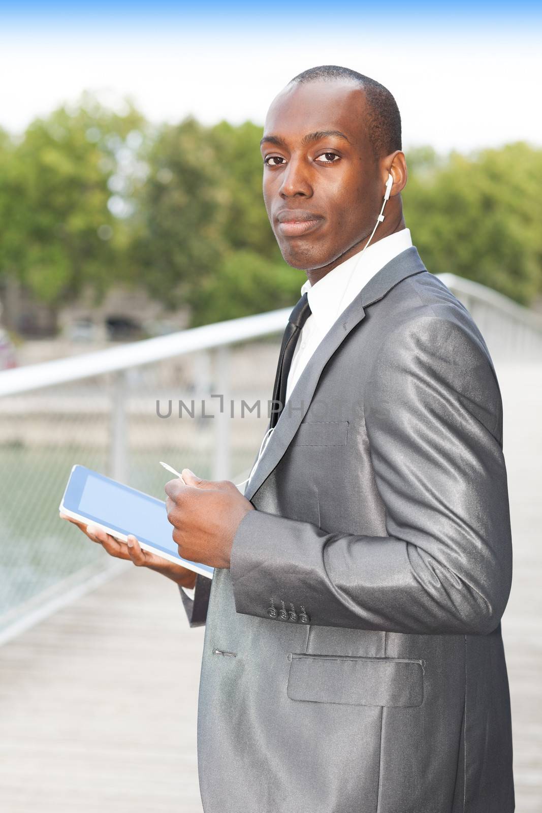 Portrait of a busy businessman using mobil phone with hands-free headset and using electronic tablet