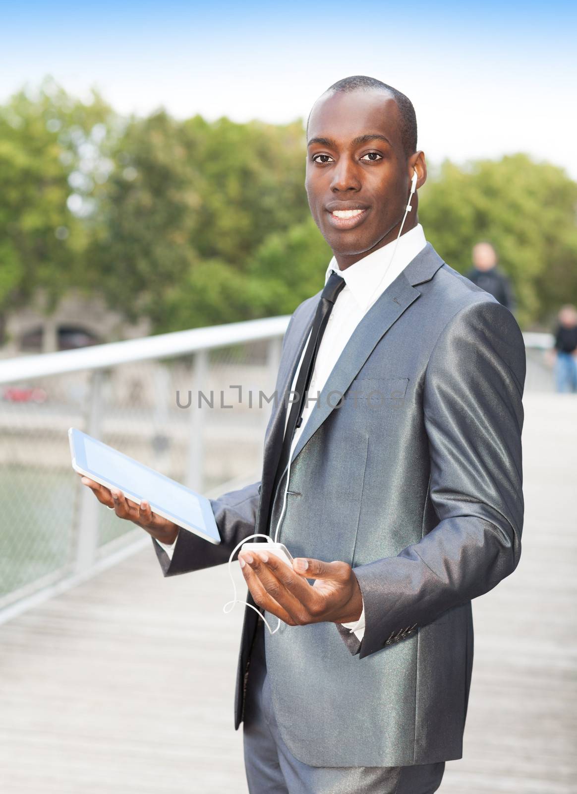 Portrait of a businessman on the phone with hands-free headset and using electronic tablet