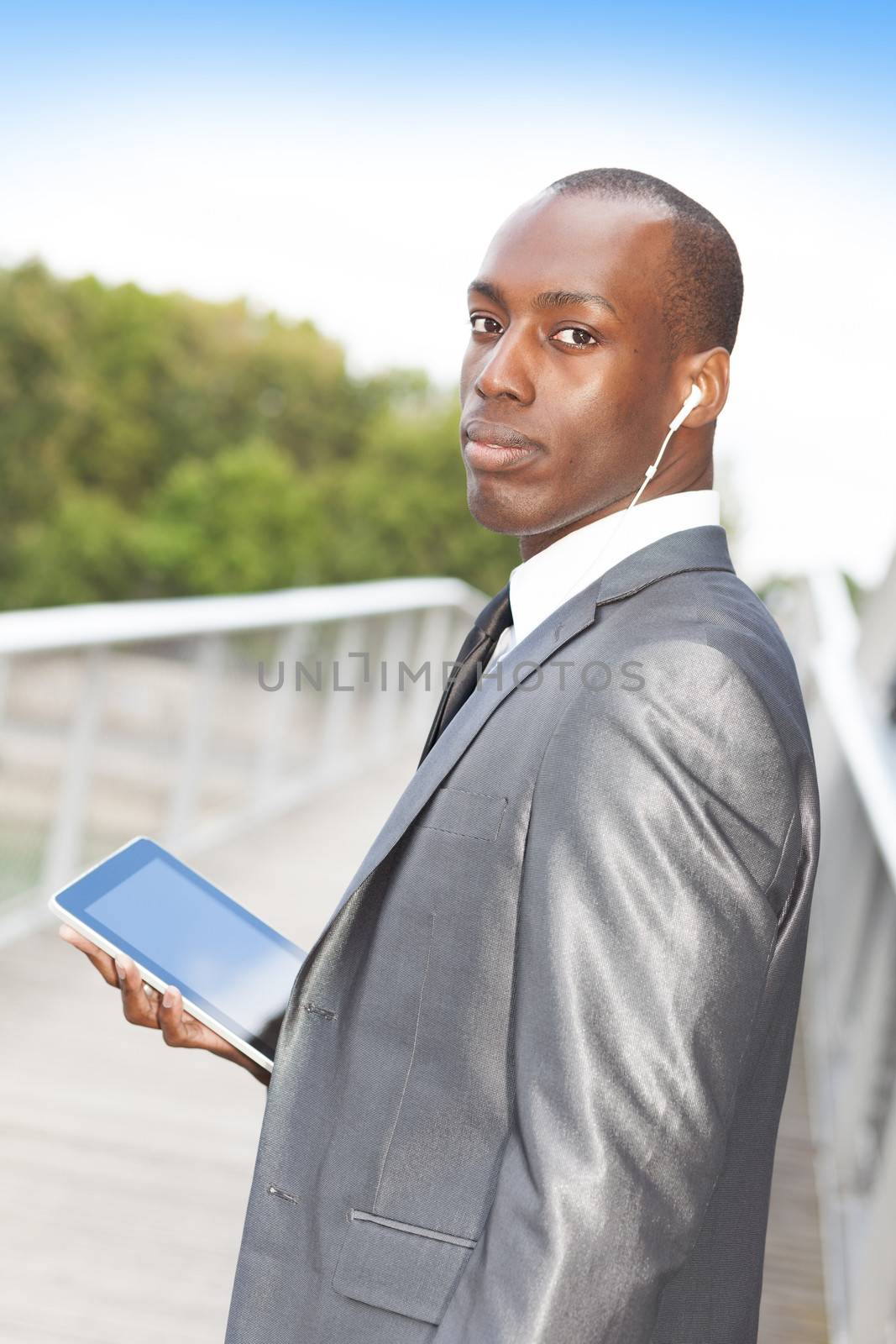 Portrait of a handsome businessman with hands-free headset and using electronic tablet