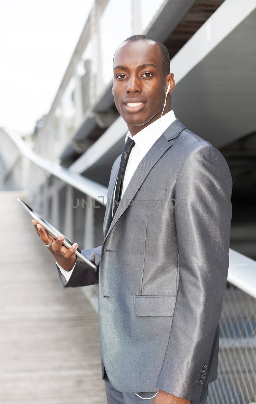 Portrait of a businessman with hands-free headset and using electronic tablet