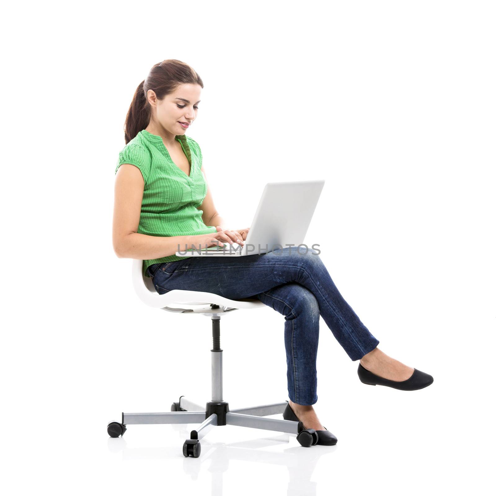 Beautiful female student sitting on a chair with a laptop, isolated over a white background
