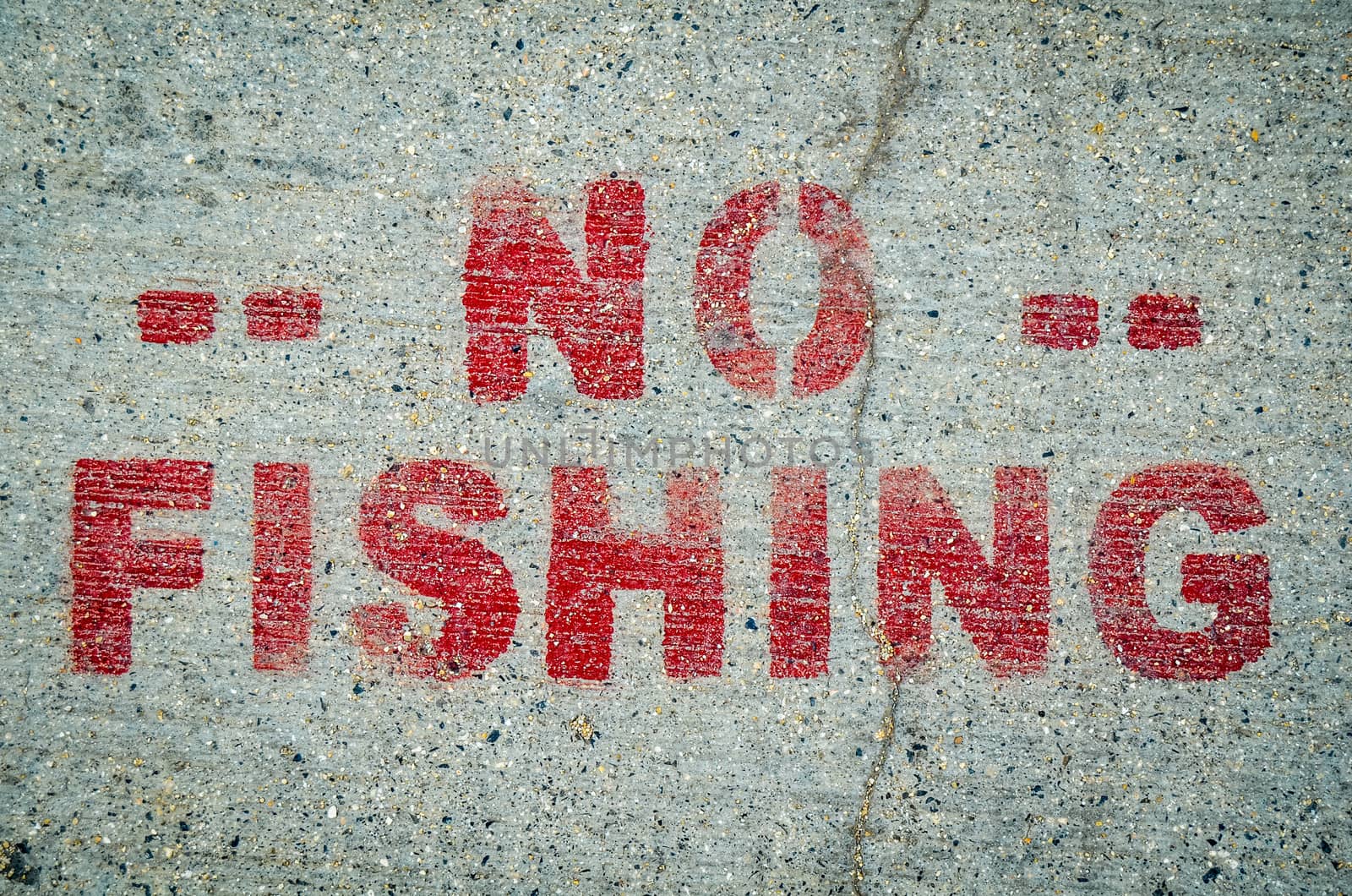 A No Fishing Sign Stamped Onto Cement By Ocean Or River