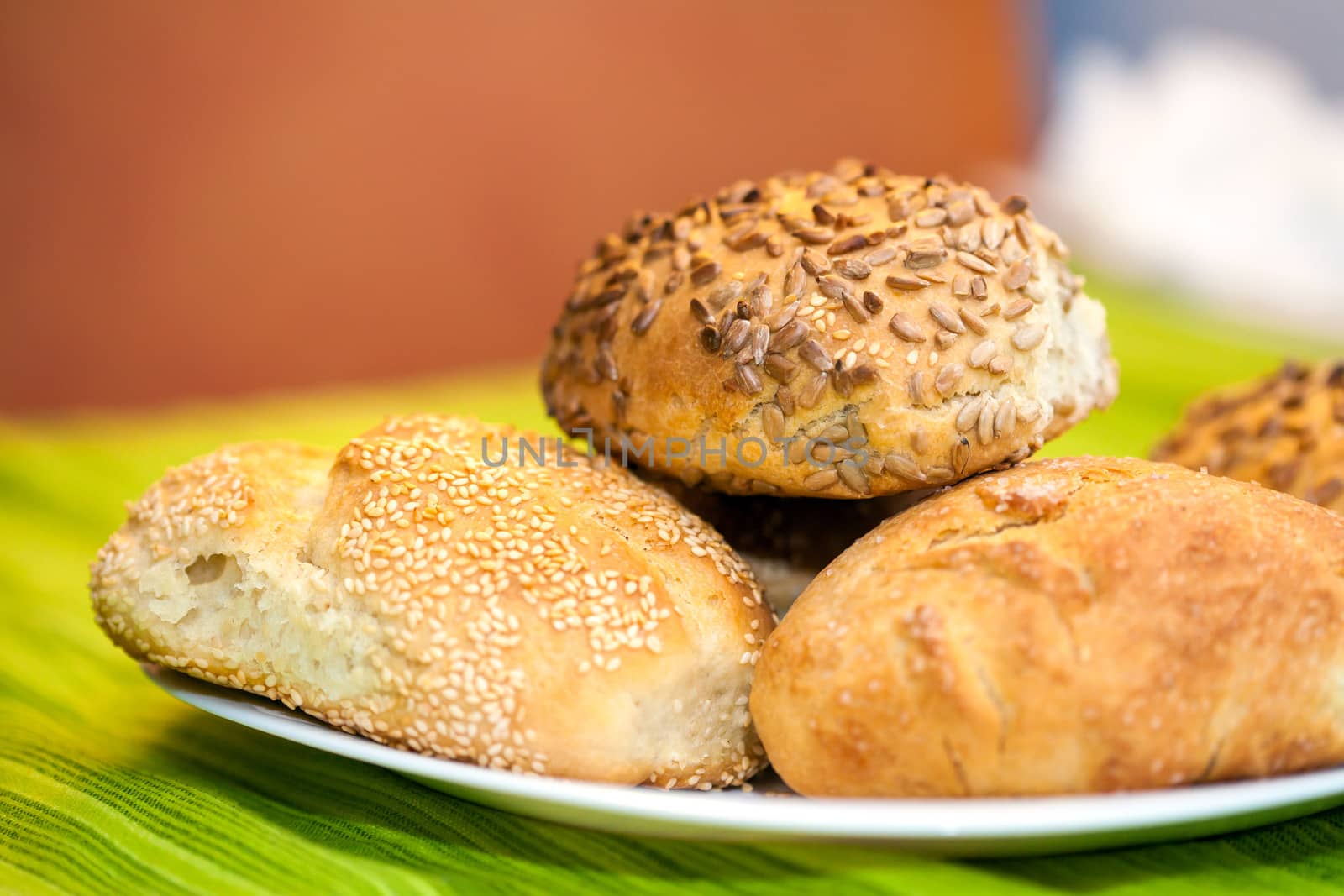 Fresh bread rolls with sunflower and sesame seeds on white plate table set
