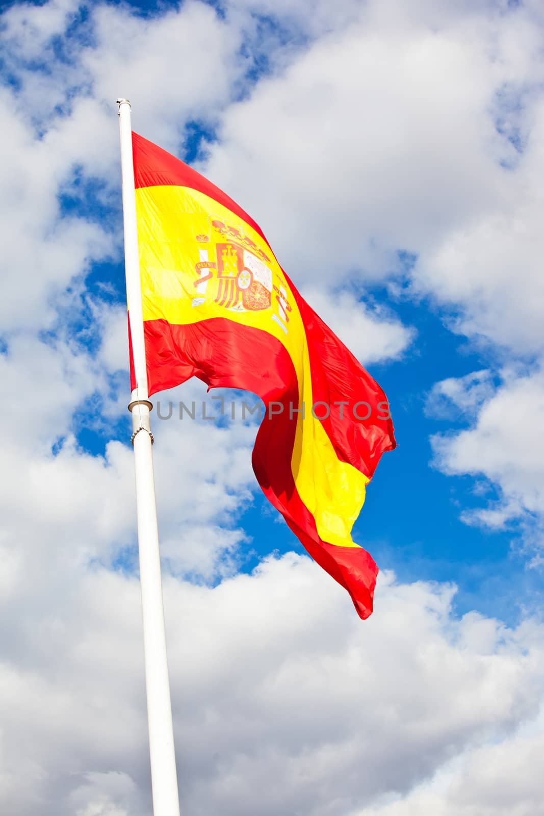 Flag of Spain over blue sky moving in wind