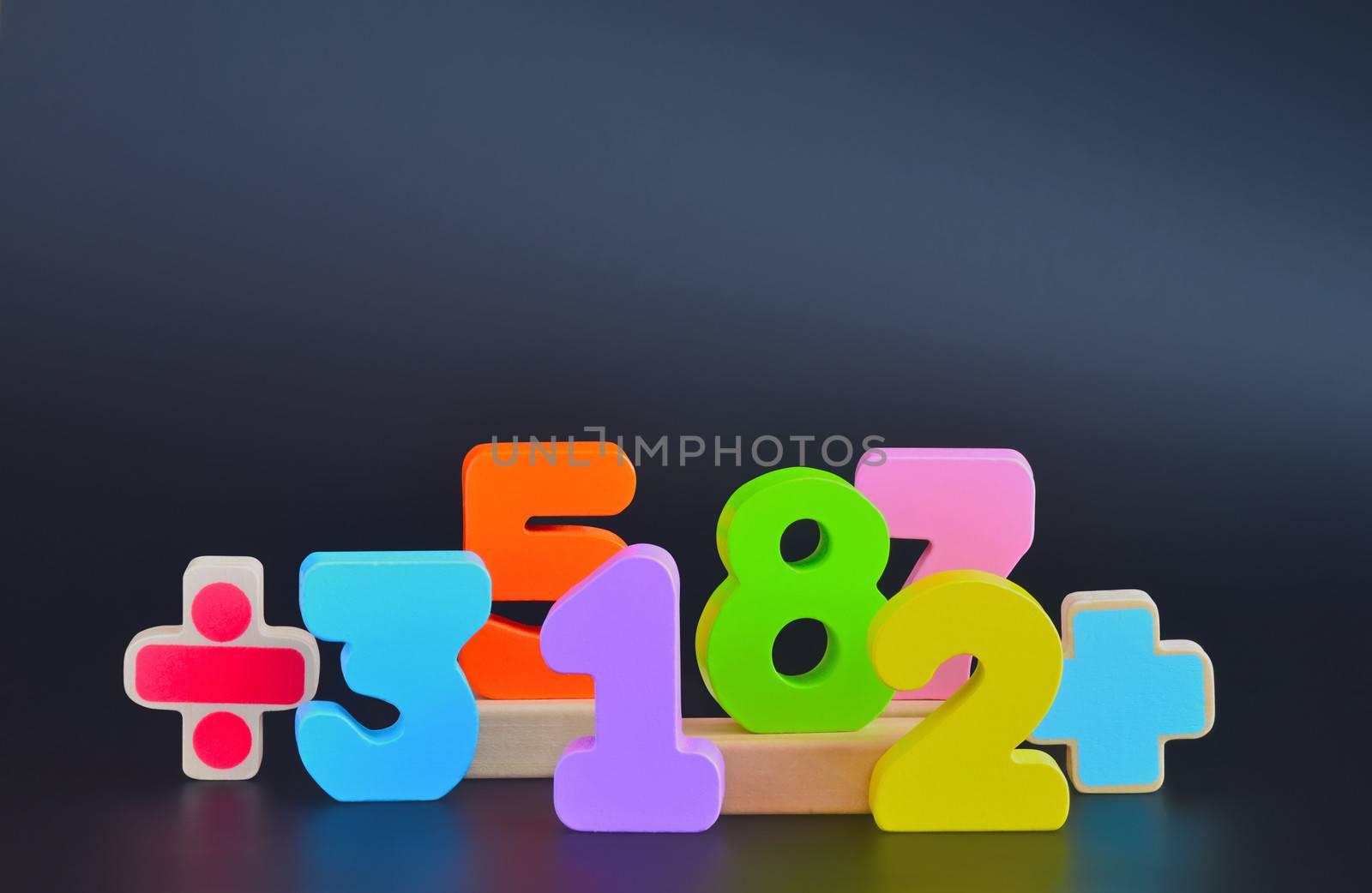 Color wodden blocks in the shapes of numbers. Dark shiny background with reflexions. Numbers with path.