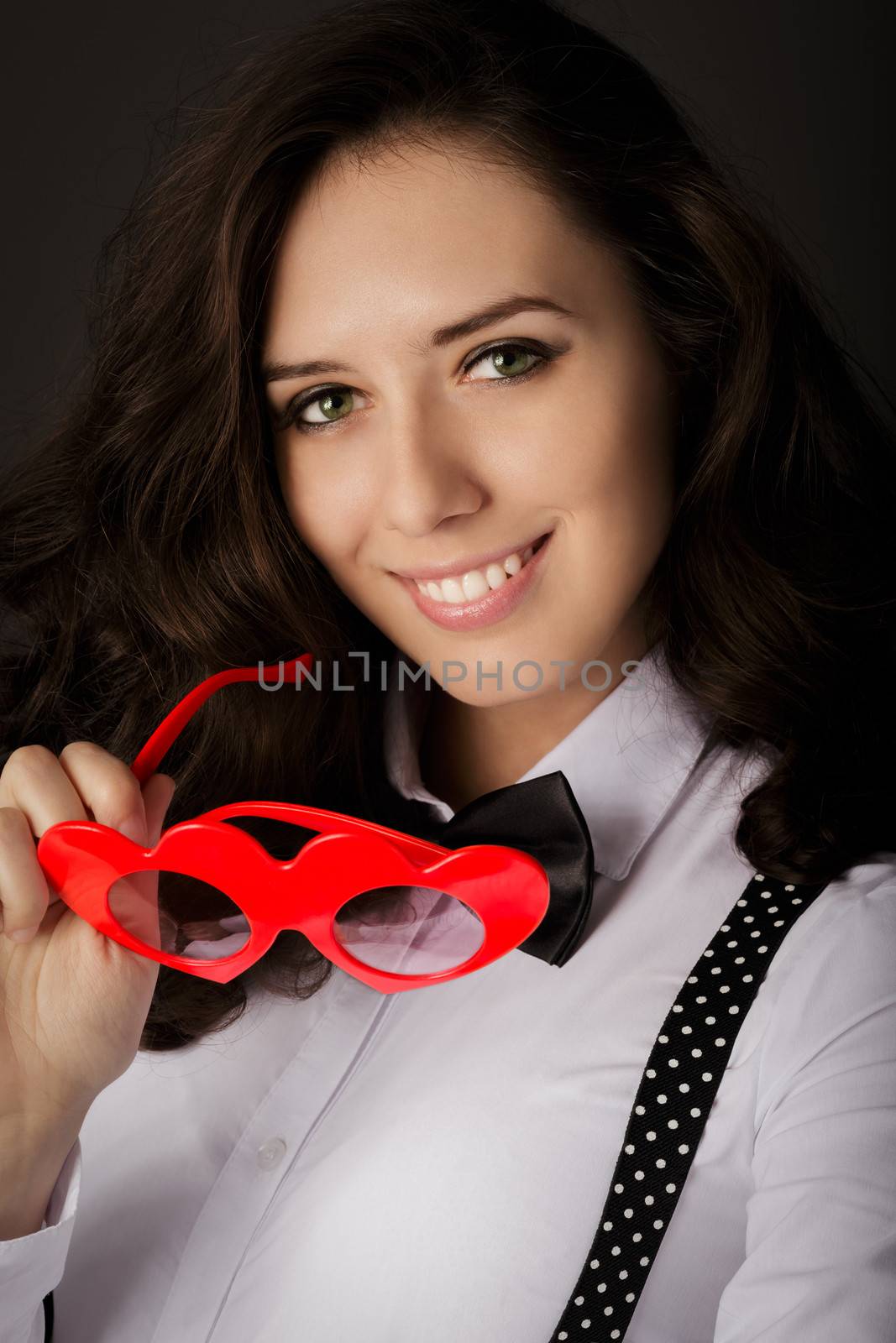 Portrait of a beautiful girl holding a pair of heart-shaped glasses.