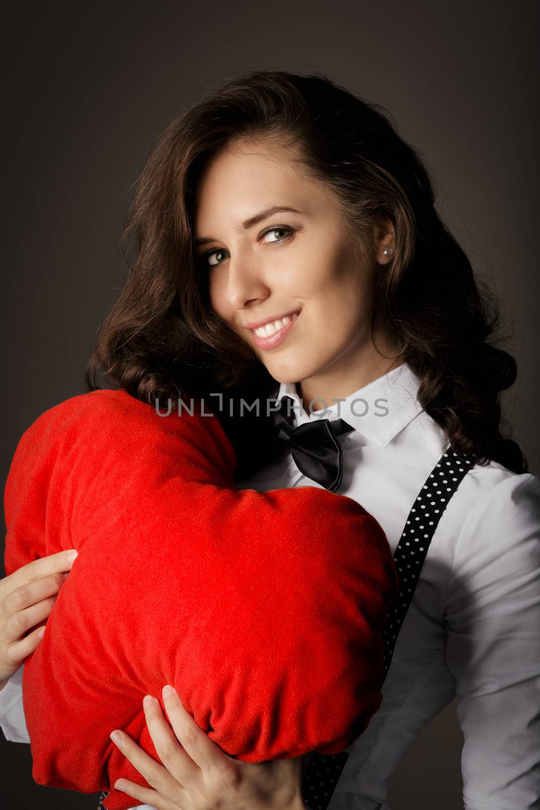 Beautiful girl holding a heart-shaped pillow in her arms.