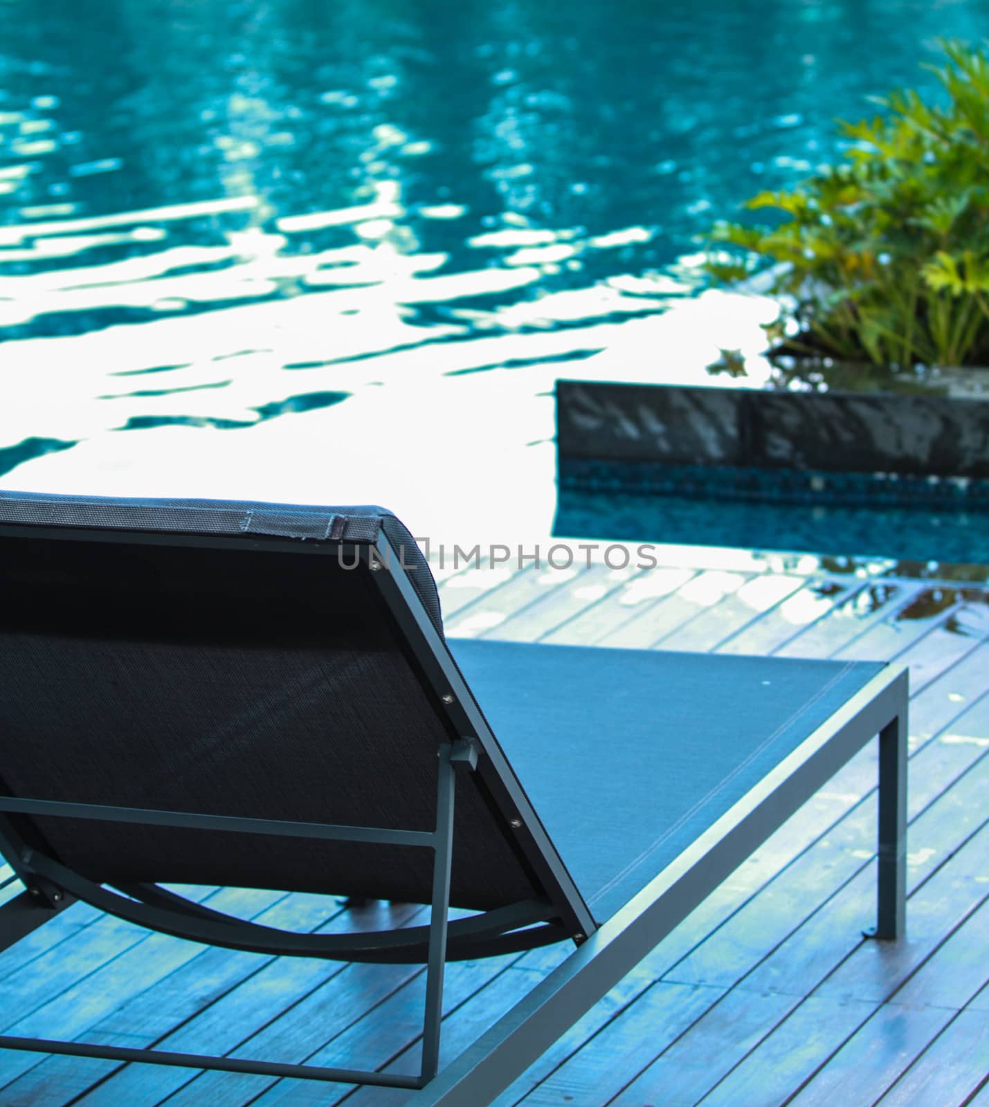 Closeup chaise longue with swimming pool background