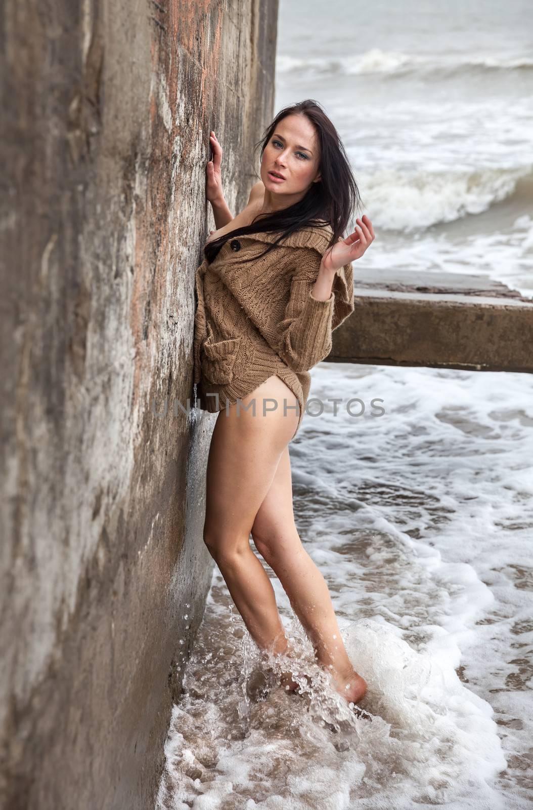Seminude woman near concrete constructions on the sea shore