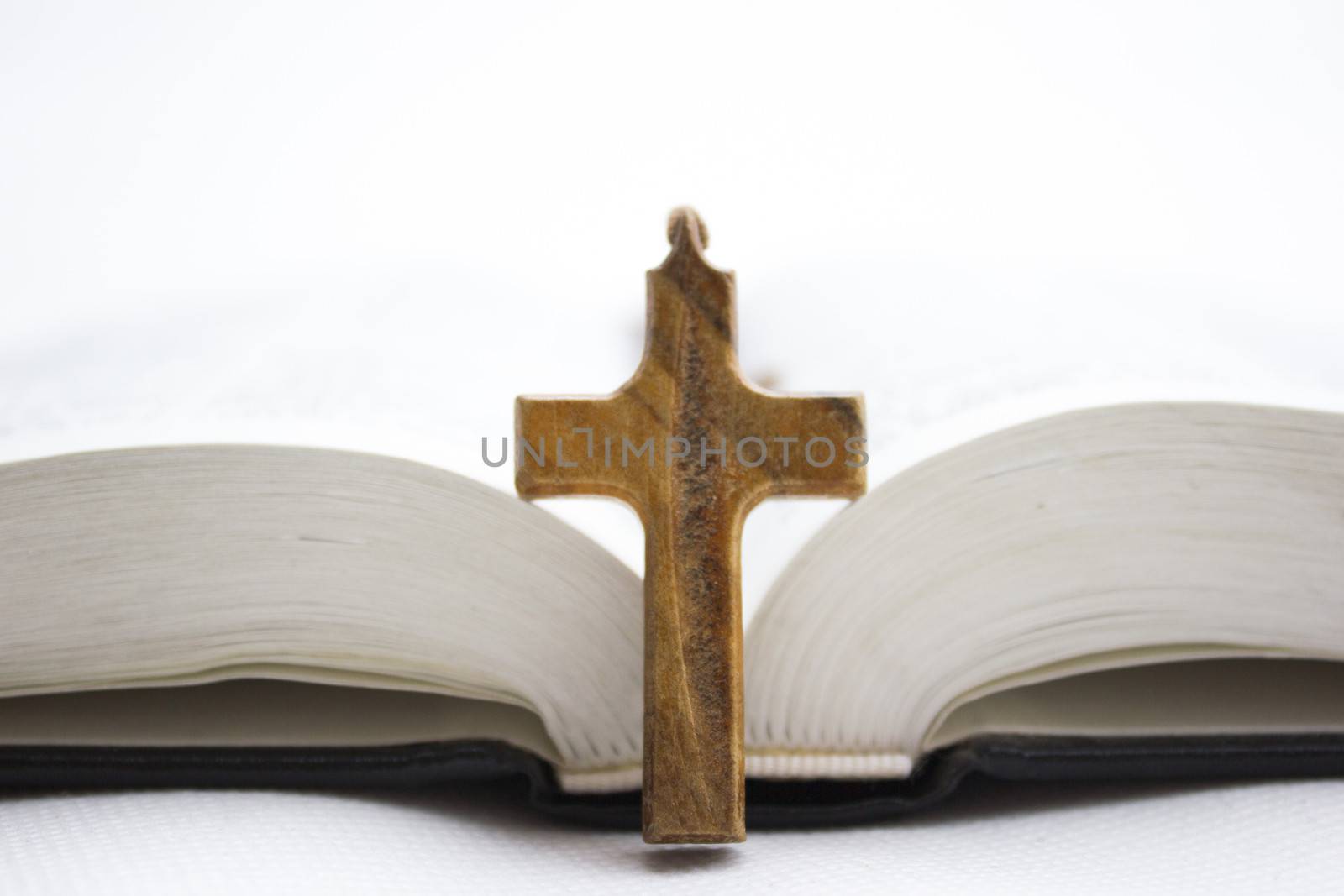 The Holy Bible with a wooden cross on top of it.